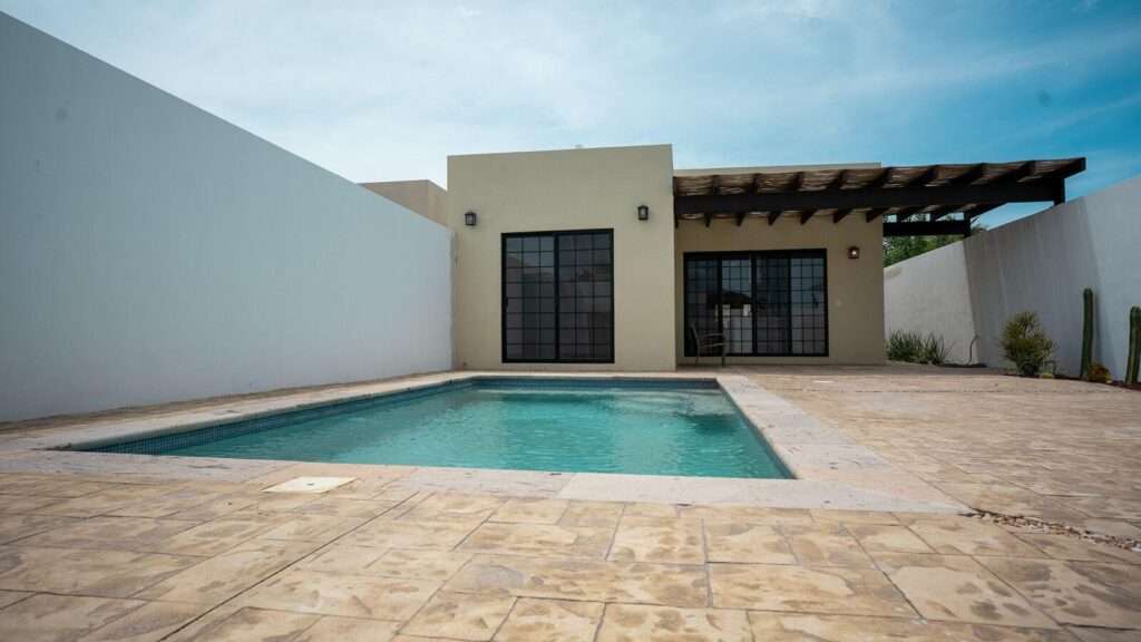 La Paz El Centenario Make this house located in a serene and safe area all yours. Its luxury finishes shine with the warmth of the parota wood, which adorns every corner, spacious bedrooms, as well as a third space for a study or bdr, it offers a refuge of comfort and tranquility, the pool invites you to relax, perfect for gatherings with friends and family. The pergola terrace offer additional spaces to enjoy the outdoors. This house is the dream come true for those looking for a luxury home in a quiet and safe environment.PROPERTY EQUIPMENT:• Pool 6.00x4.00 meters with machine room.2 automatic anti-cyclone metal curtains.Pool deck with stamped concrete.Stamped concrete walkers, fridge, AC inverter, *Ugradepackage to built BBQgrill& equipped with a wood-burning oven, and concrete bar – 845 LAZARO CARDENAS, La Paz, BS