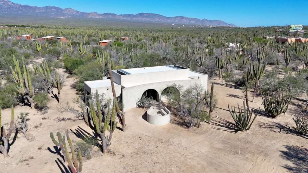 La Paz La Ventana Casa Moya - a brand-new 1-bedroom, 1.5-bath architectural retreat nestled in La Ventana's magical Cardon forest. Thoughtfully designed for those who appreciate artful living and beautiful surroundings, this distinctive home blends modern desert architecture with natural landscape. Soft sculptural lines and smooth curves create a striking yet harmonious aesthetic, while large arched openings frame surrounding cacti and desert sky. Nearing completion, the home offers a rare opportunity for the buyer to select certain finishes and add a personal touch. Ideal as a serene full-time residence, vacation escape, or stylish desert retreat where architecture and nature meet beautifully. The circular outdoor fire pit seating area invites evenings with friends beneath spectacular star filled skies. – Comunidad Bruma, La Paz, BS